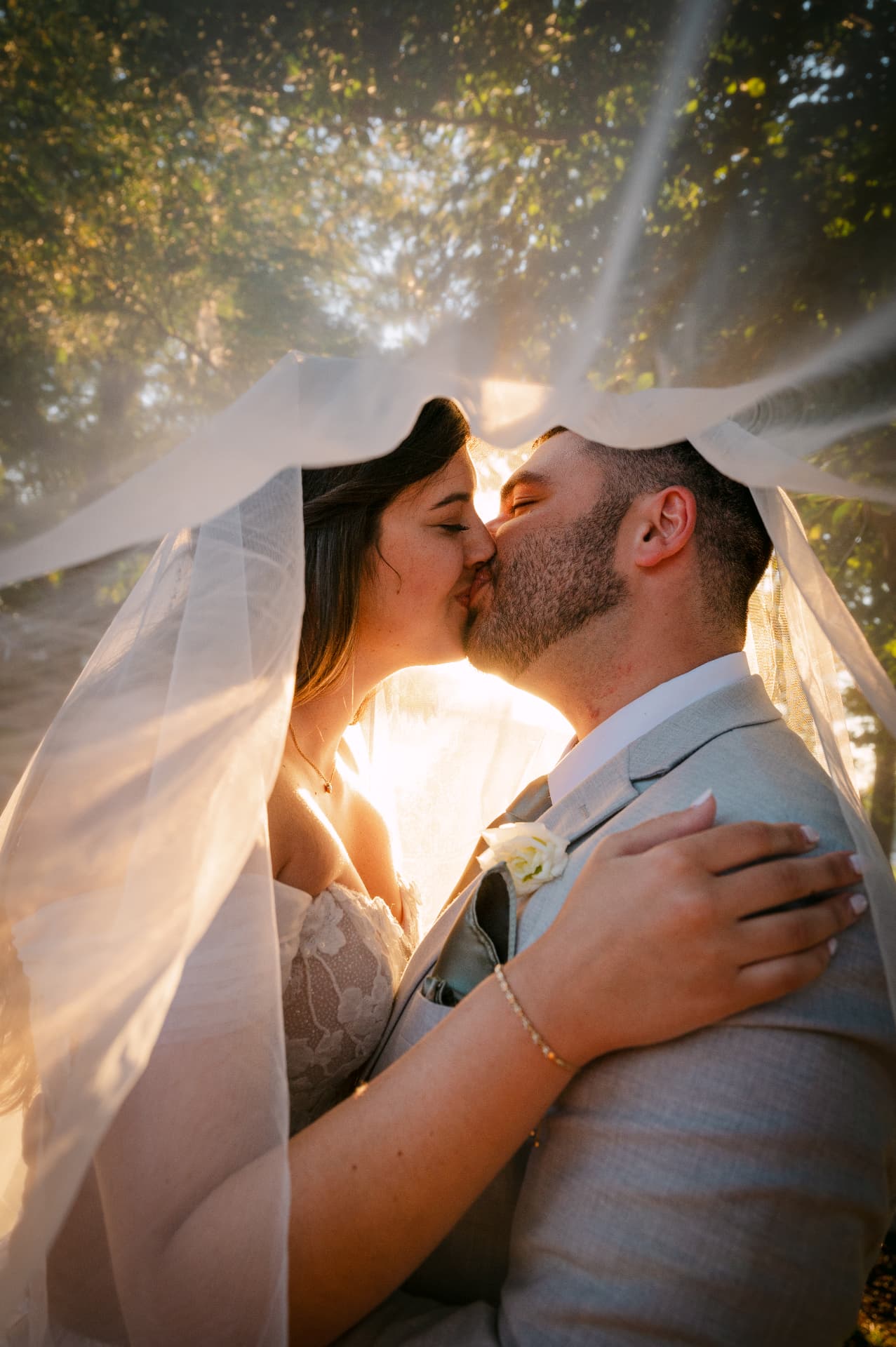 Couple kissing under the veil in backlit sunset light