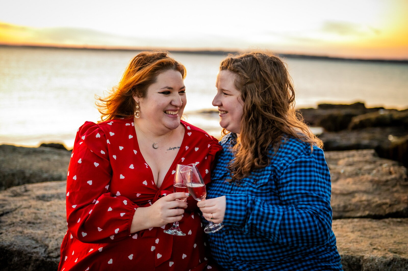 Two brides toasting at sunset by the water