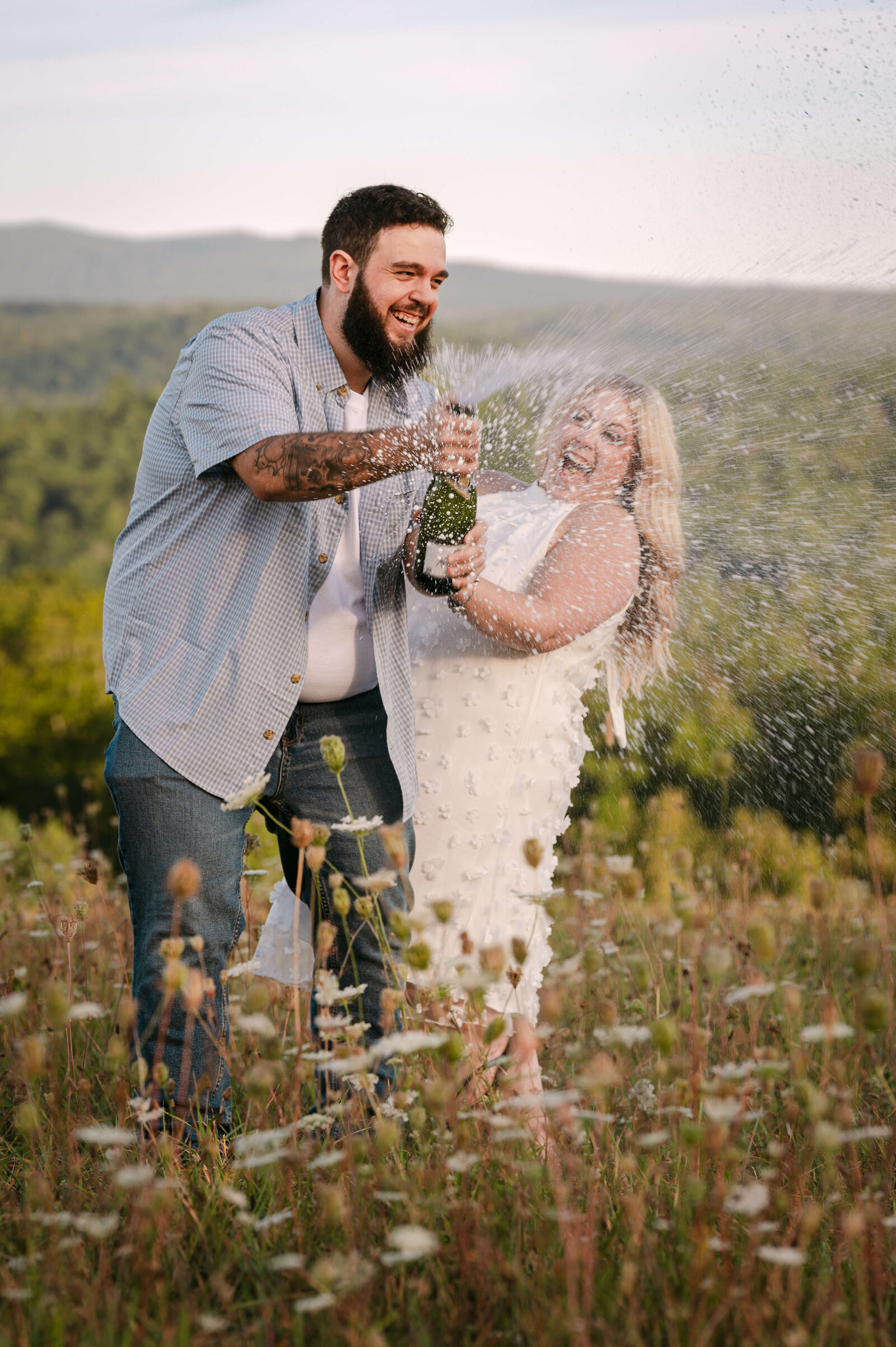 Couple popping champagne in a wildflower field