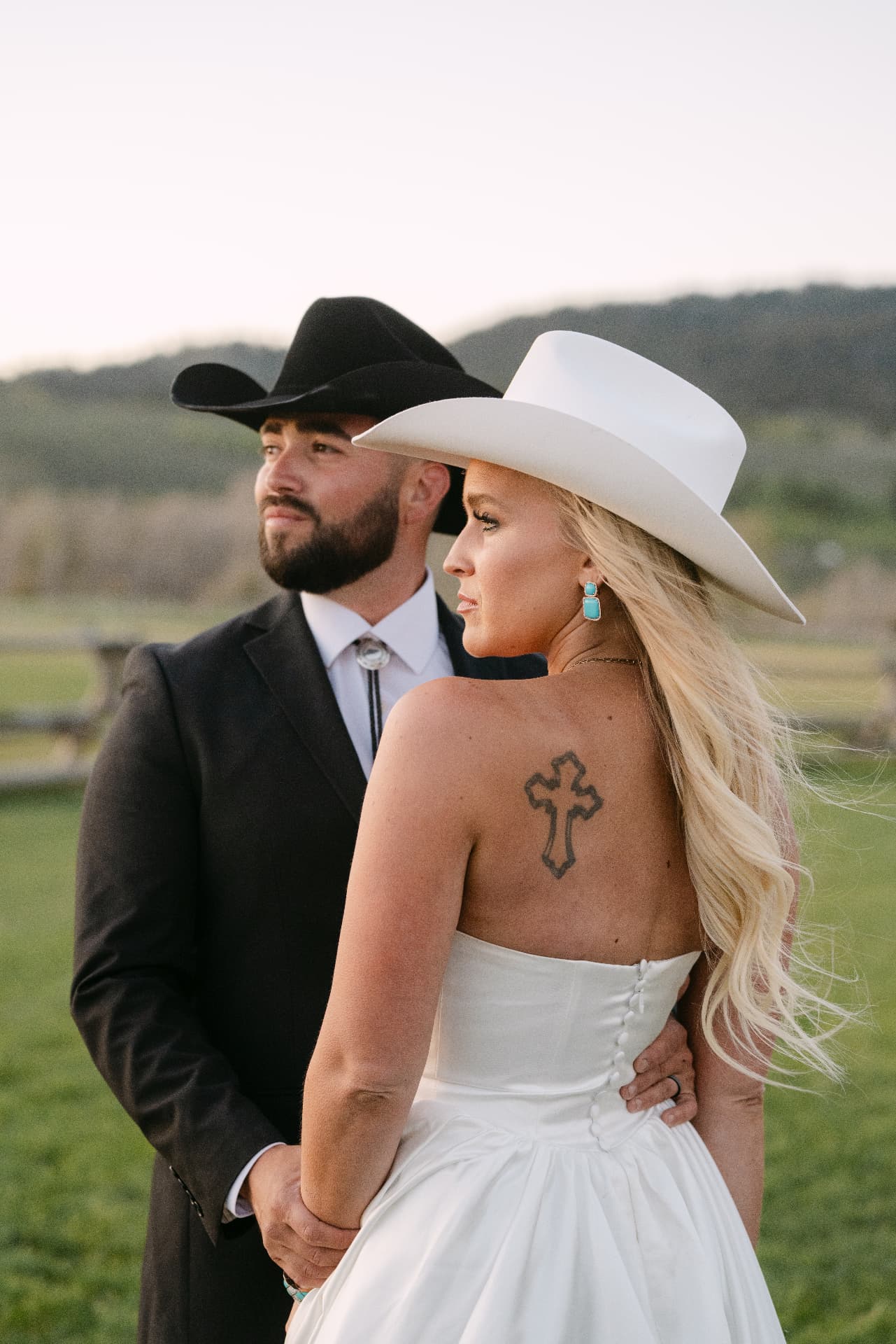 Bride and groom in cowboy hats at a ranch wedding at sunset